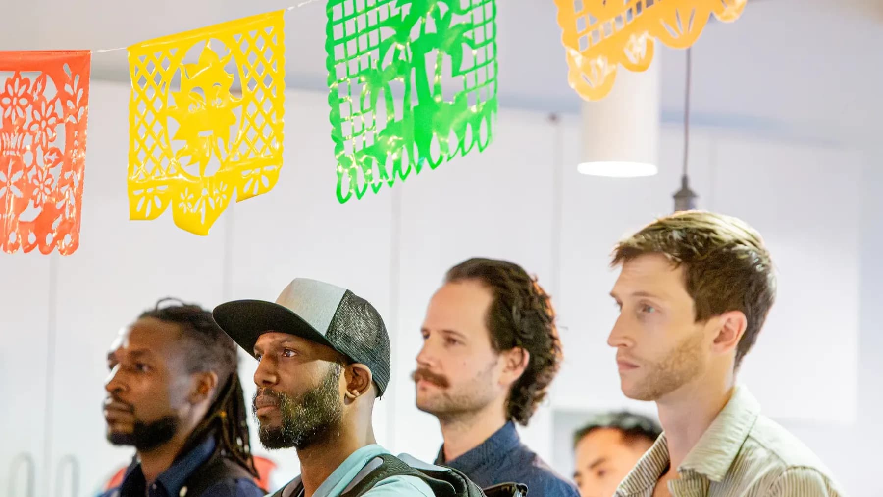 Austin attendees listening beneath colorful papel picado at the first Code for Community meetup