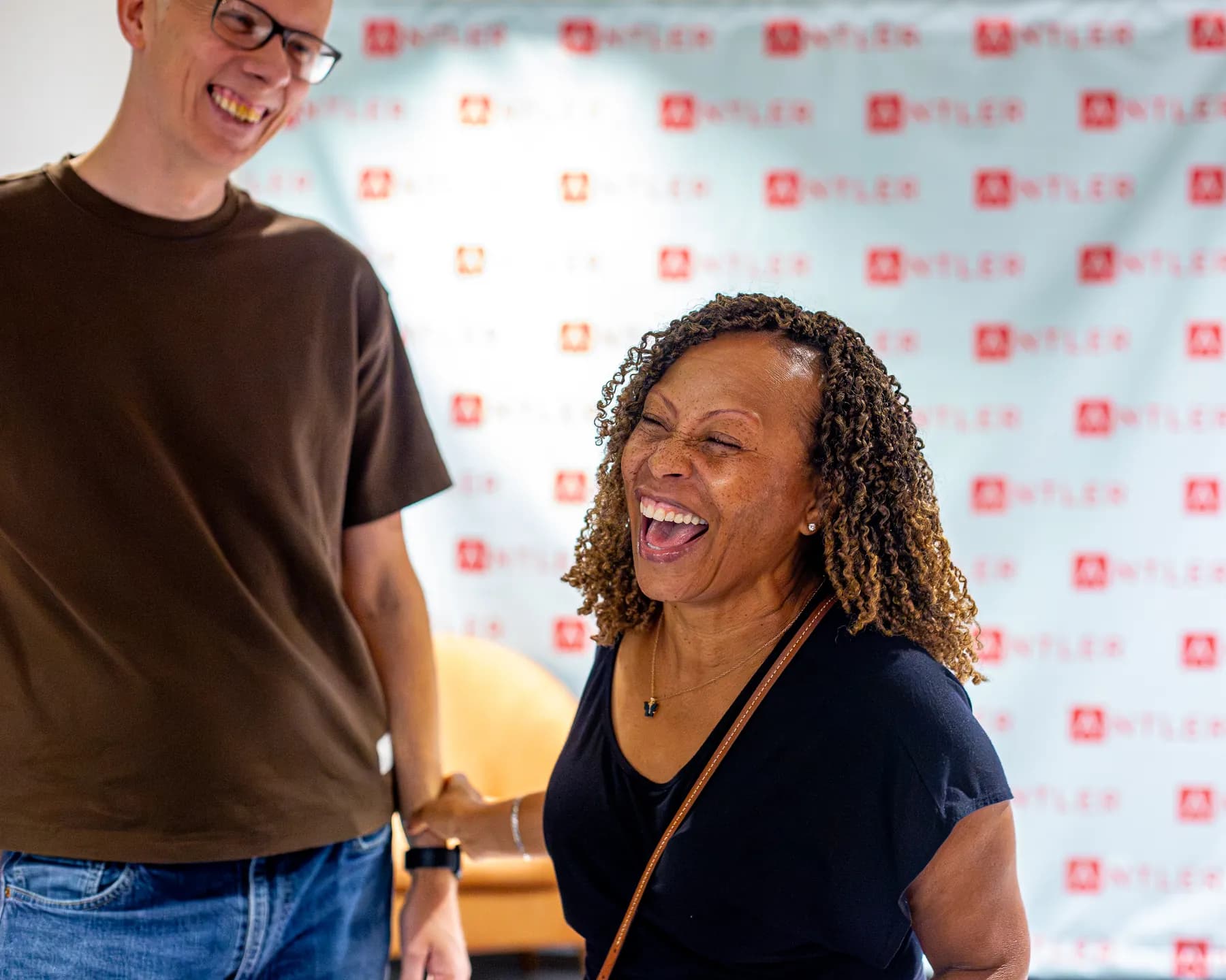 An attendee laughs during a conversation in front of the Antler backdrop